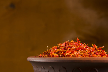 Saffron spices in clay pots on a wooden backgroundの写真素材