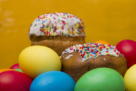 Easter eggs of different colors and cake on a wooden background