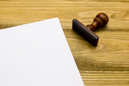 Wooden stamp and a sheet of paper on a wooden tableの写真素材