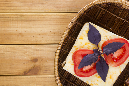 Open sandwich in a wicker basket on a wooden tableの写真素材