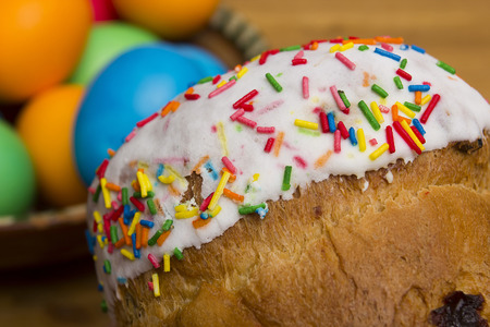 Easter eggs of different colors and cake on a wooden background