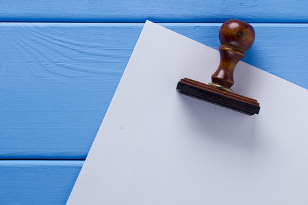 Wooden stamp and a sheet of paper on a wooden tableの写真素材