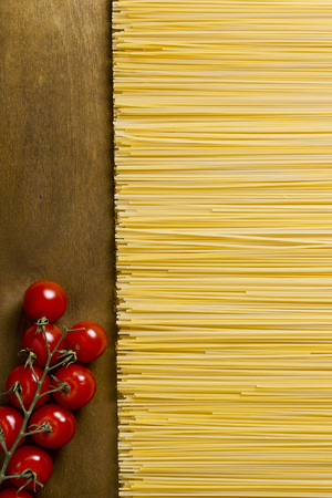 Spaghetti and tomatoes on a dark wooden backgroundの写真素材