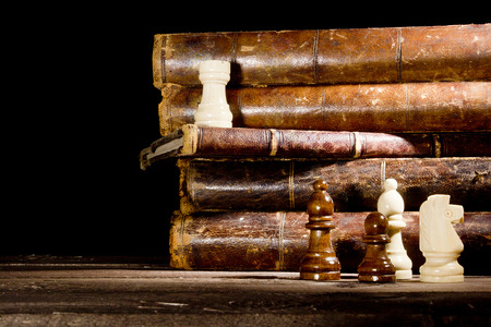 Old books and chess pieces on a black backgroundの写真素材