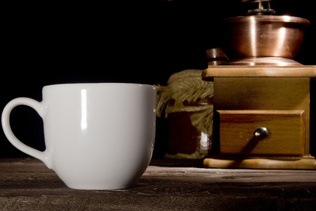 Cup of coffee and grinder on wooden tableの写真素材