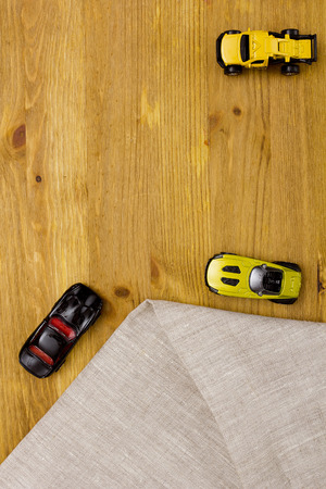 Toy models of cars and a linen cloth on a wooden tableの写真素材