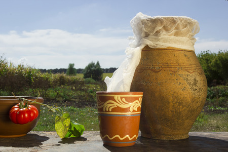 Clay jug with milk on a background of the rural landscapeの写真素材