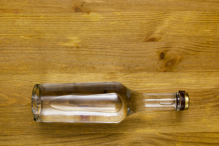 Full bottle of vodka, a bottle lying on a wooden surface.の写真素材