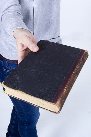 Female hand holding an old book on a white backgroundの写真素材