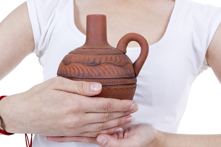 Clay pitcher in female hands on a white backgroundの写真素材