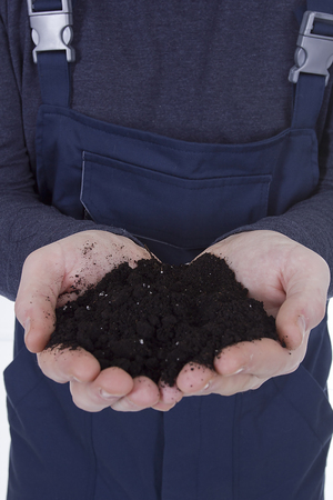Black soil in the hands of a young farmerの写真素材