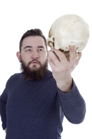 Bearded man with a human skull in his handの写真素材