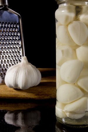 Marinated and fresh garlic with a grater on a dark backgroundの写真素材