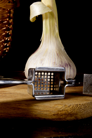 Garlic press and cloves of garlic laid on a wooden table backgroundの写真素材