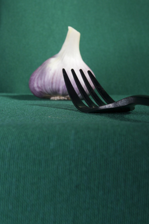 Fork and garlic on a green backgroundの写真素材