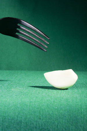 Fork and garlic on a green background
