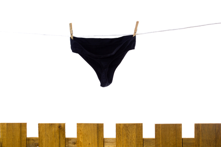 Female underwear dries on a rope behind a fenceの写真素材