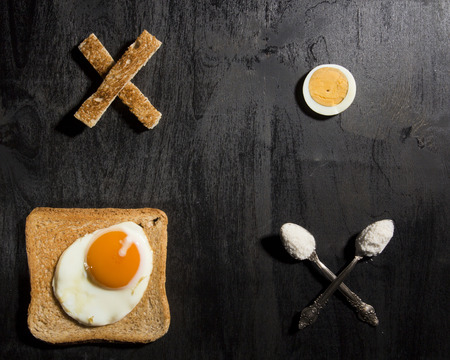 Breakfast option with egg on a black wooden boardの写真素材