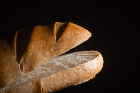 Cut loaf of bread on a black background
