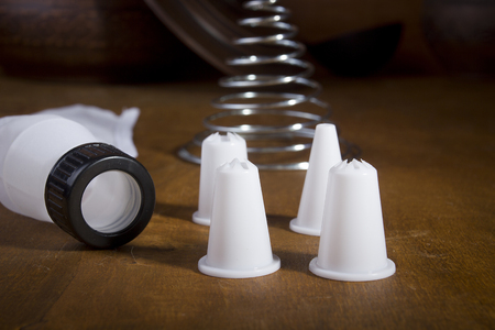 Confectionery bag for baking and a nozzle to it on a wooden tableの写真素材