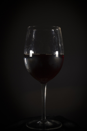 Glass with red wine on a black backgroundの写真素材