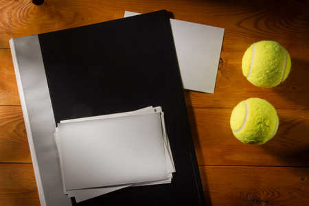 Folder with photos with tennis balls on a wooden tableの写真素材