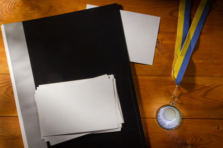 Folder with photos and medal on a wooden table