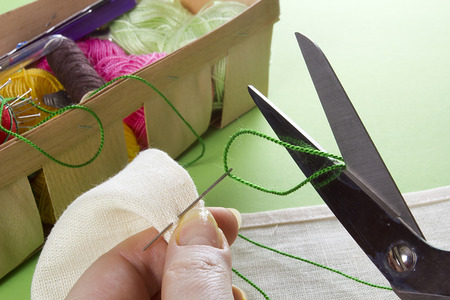 Closeup of hands with thread and needle sewing tools