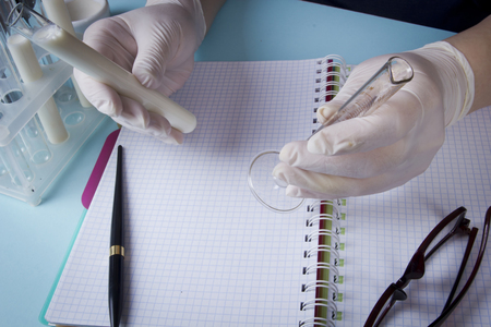 Hands in latex gloves with test tubes record in a notebookの写真素材