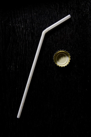 White straw for cocktails on a black wooden surfaceの写真素材