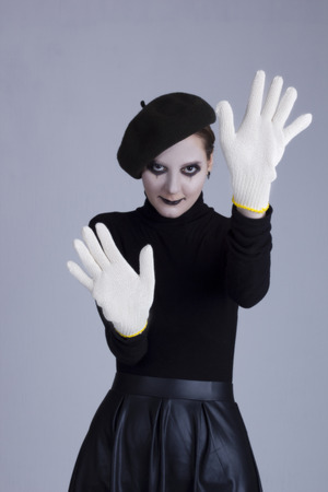 Young woman mime in gloves on a gray backgroundの写真素材