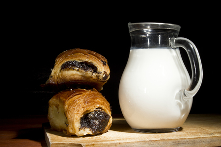 Sweet baking in a wooden plate and milk in a glass bowlの写真素材