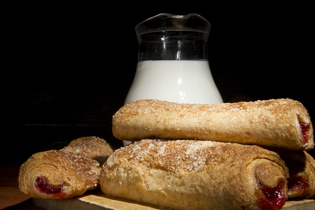 Sweet baking in a wooden plate and milk in a glass bowlの写真素材