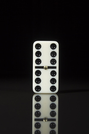 One domino tile on a black reflective surface