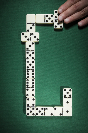Businessman playing with dominoes and holding a tile, strategy and management conceptの写真素材