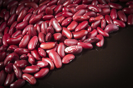 Red beans on a black reflective surface