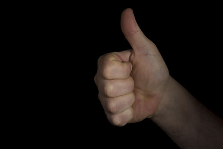 Hand with thumb up on black background