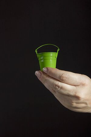 Female hand with a small green bucketの写真素材