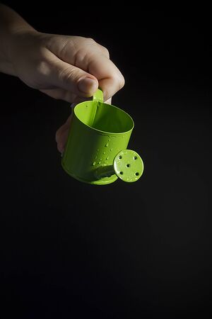 Female hand with a small green watering canの写真素材