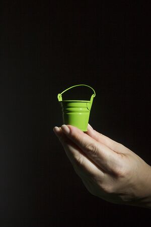 Female hand with a small green bucketの写真素材