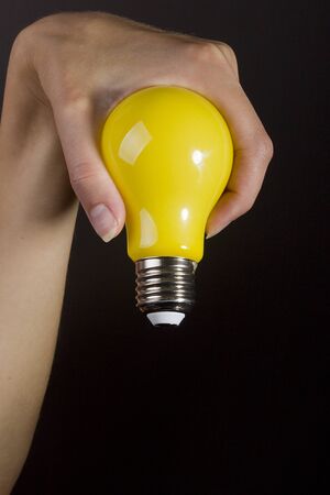 Female hand with a yellow light bulbの写真素材