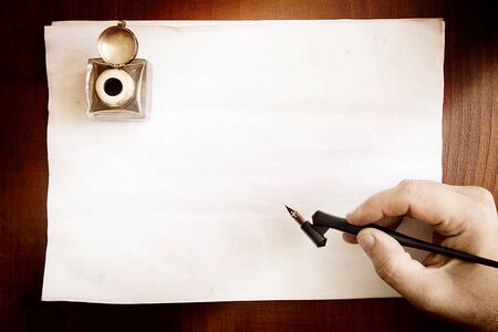 Hand with fountain pen on blank paper background