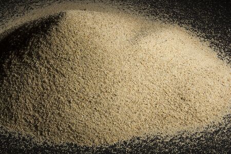 A pile of sand on a black reflective surface