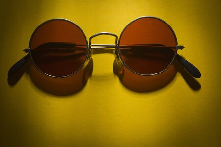 Round sunglasses on the table with yellow coatingの写真素材