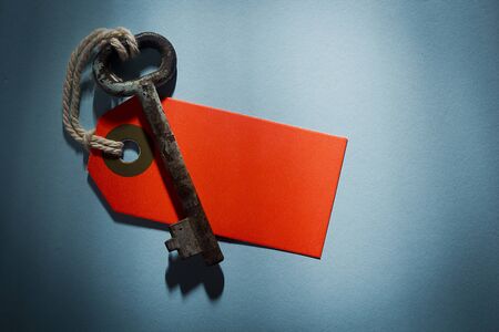 Old key with red tag on a blue tableの写真素材