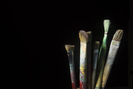 Artist's brushes in paint on a black backgroundの写真素材