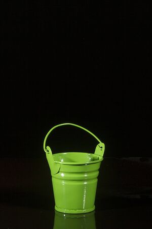 Small green bucket on a black reflective backgroundの写真素材