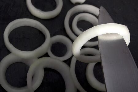 Onion rings and knife on a black backgroundの写真素材