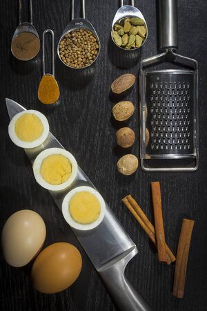 Spices in metal spoons and eggs on a black backgroundの写真素材