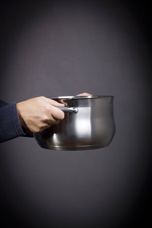 Metal pan in male hands on a black backgroundの写真素材